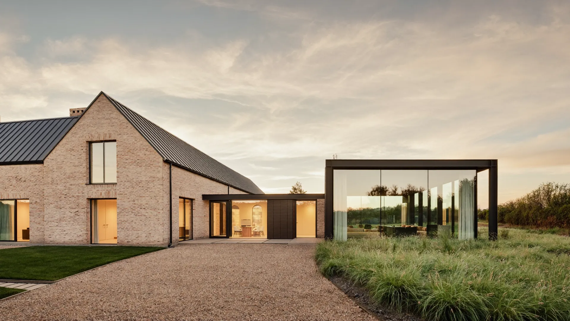Gerenoveerde boerderijwoning met moderne glazen aanbouw in de avond